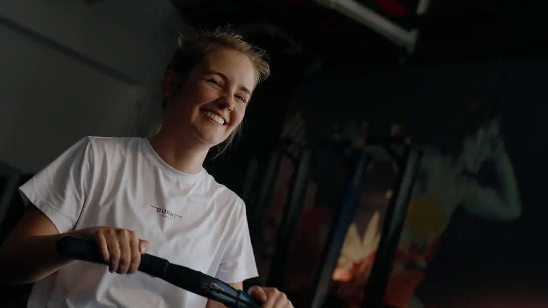 A member laughing mid-workout on a rowing machine